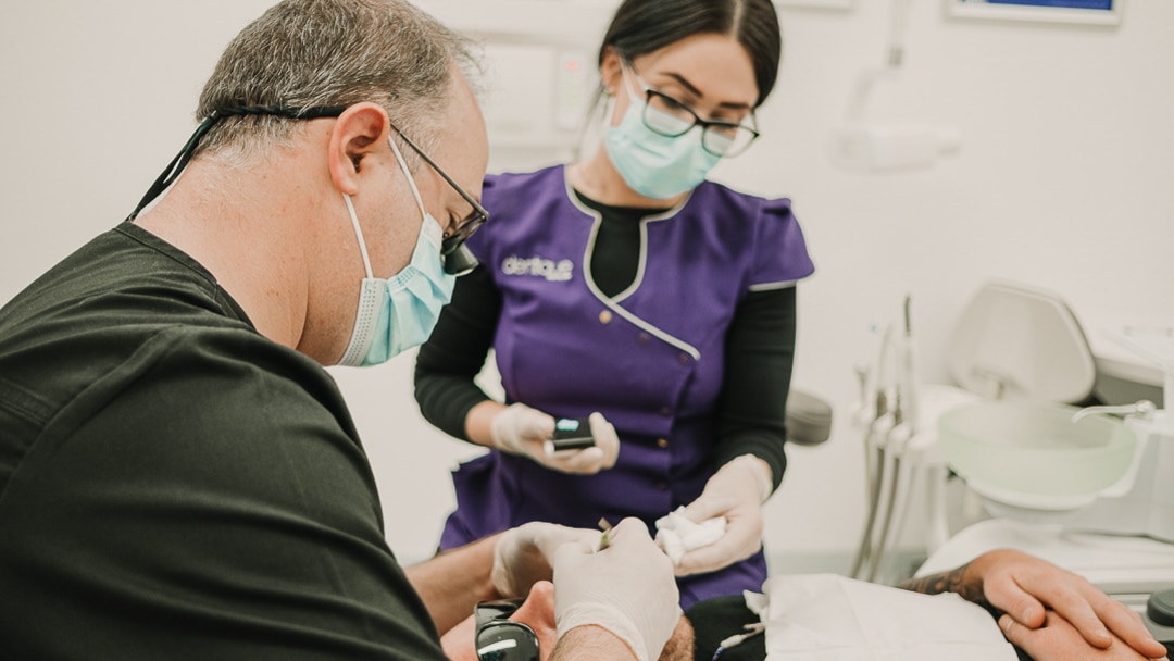 an image of a dentist and a dental assistant checking up on a patient fro invisalign